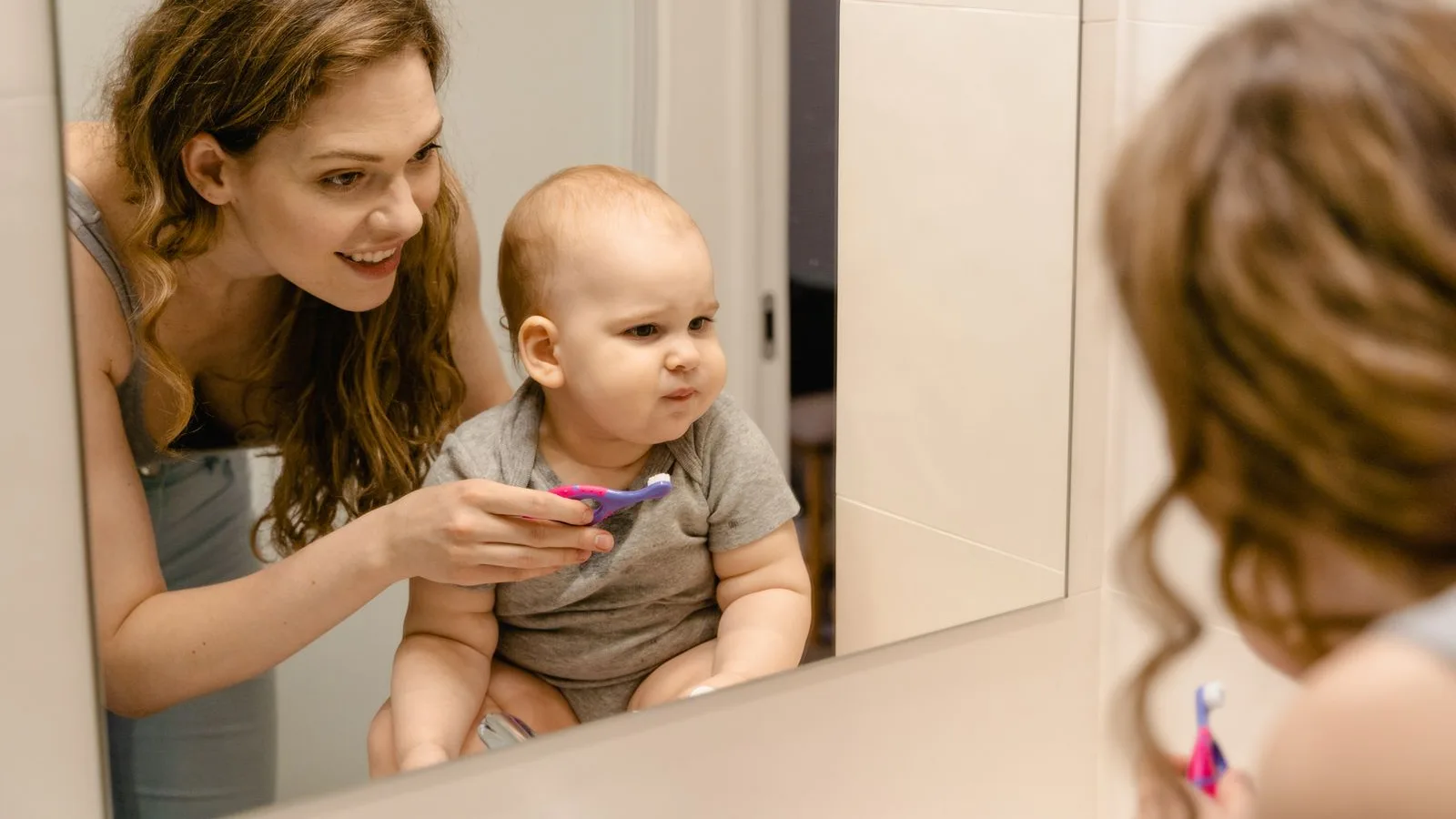Parent helping a young child brush their teeth at home