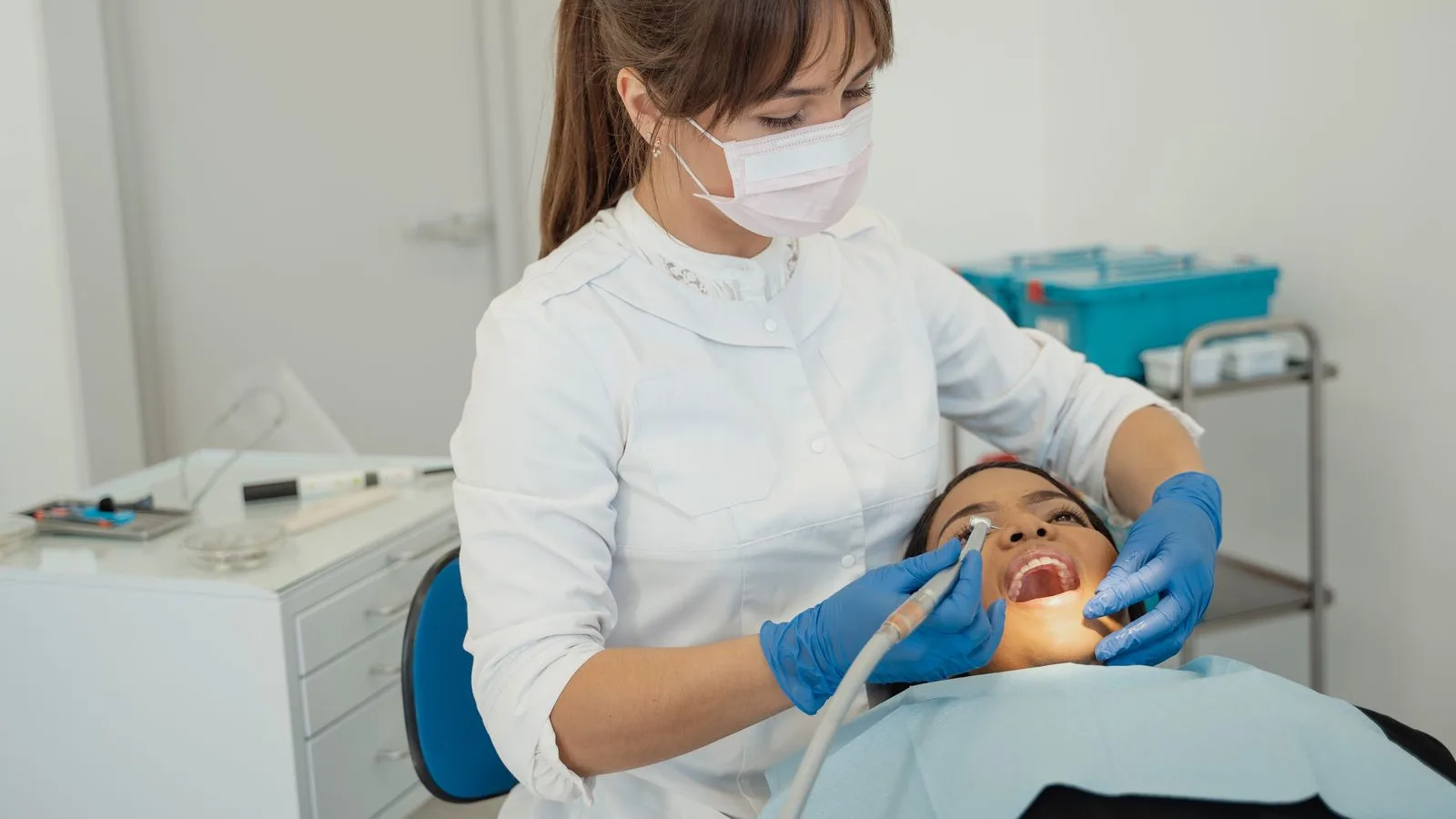 Dental hygienist treating a reclined patient in a bright modern clinic